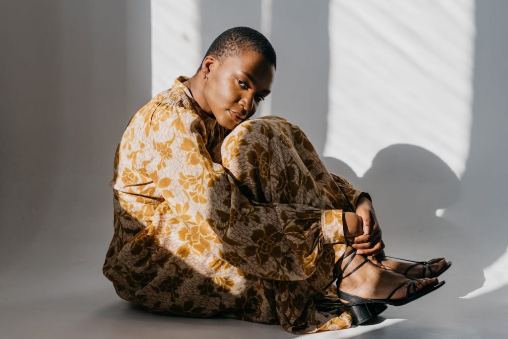 Elegant fashion portrait of a woman in a floral dress sitting gracefully indoors.